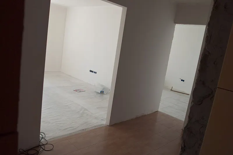 Plasterer finishing a smooth gypsum ceiling soffit and skimmed walls in a Maltese apartment