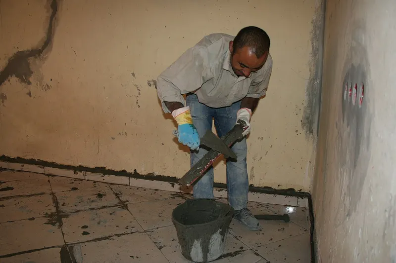 Tiler laying large-format rectified porcelain floor tiles with levelling clips in Malta